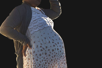 Midsection of woman standing against black background