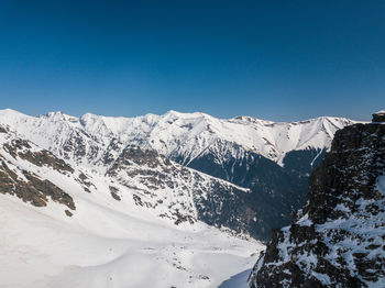 Scenic view of snowcapped mountains against clear blue sky