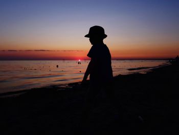 Silhouette man standing on beach against sky during sunset