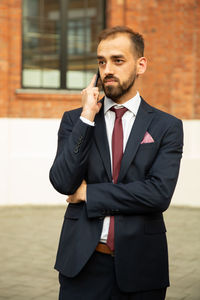 Businessman talking on smart phone on footpath