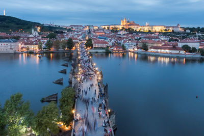 High angle view of illuminated city by river against sky