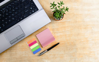 Directly above shot of laptop with adhesive notes on wooden table