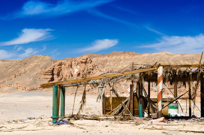 Lounge chairs on sand at beach against blue sky