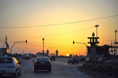 Cars moving on road against clear sky at sunset