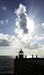 Silhouette building on beach against sky