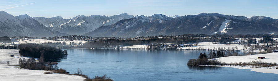 Scenic view of lake by snowcapped mountains against sky