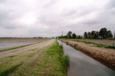 Road amidst field against sky