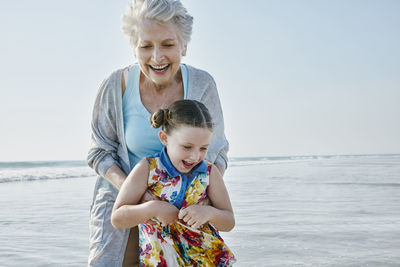 Happy grandmother with granddaughter on the beach