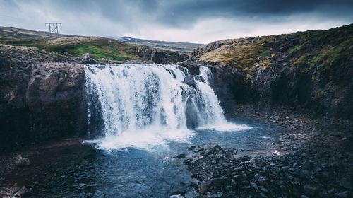 Scenic view of waterfall against sky