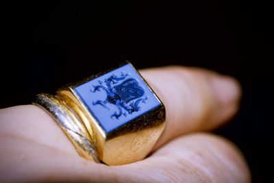Close-up of hand holding paper against black background
