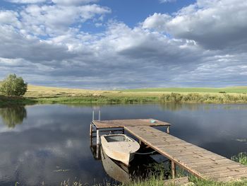 Boat moored on lake against sky