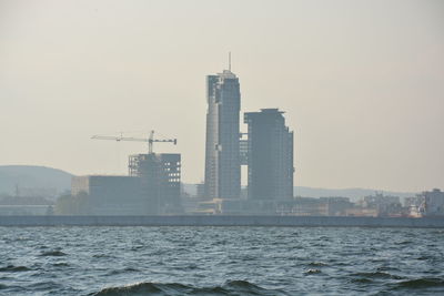 Modern buildings by sea against sky in city