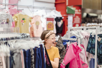 Smiling girl in supermarket looking at clothes