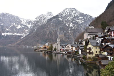 Houses by lake against mountains during winter