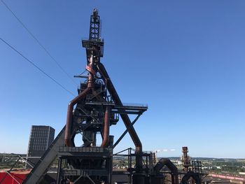 Low angle view of crane against clear blue sky