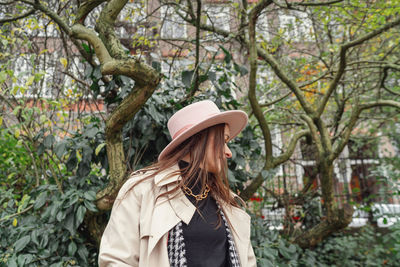 Woman standing by tree against plants