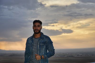 Portrait of young man standing against sky during sunset