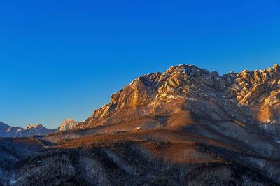 Low angle view of mountains against clear blue sky