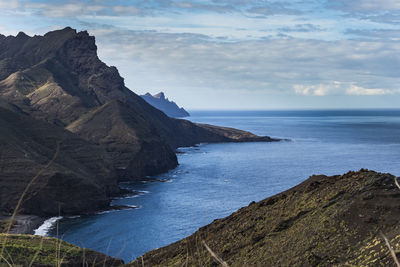 Scenic view of sea and mountains against sky