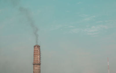 Low angle view of smoke emitting from chimney against sky