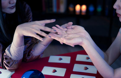 Midsection of woman playing with tattoo on table