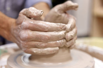 Cropped hands making pottery at workshop