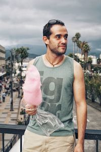 Man holding cotton candy while leaning against railing 