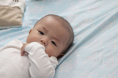 Portrait of cute baby lying on bed