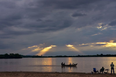 Silhouette boats in sea against sky during sunset