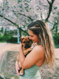 Young woman with dog against plants