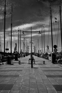 Sailboats on harbor by sea against sky