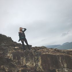 Full length of woman standing on rock against sky