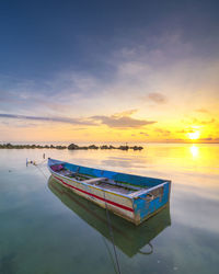 Boat moored on sea against sky during sunset