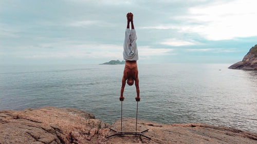 Young adult man doing circus acrobatic handstand upside down on mountain in brazil during day light