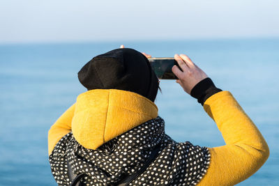 Rear view of person photographing sea