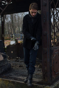 Full length of young man wearing warm clothing while standing at cemetery