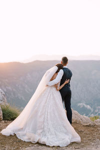 Rear view of woman with arms outstretched against mountain