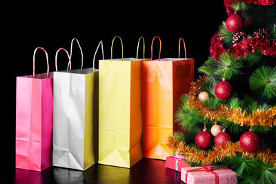 Close-up of shopping bags and christmas decorations over black background