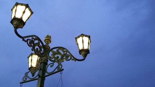 Low angle view of illuminated street light against clear blue sky