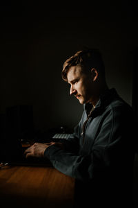 Young man using laptop in darkroom