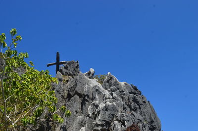 Low angle view of bird on rock against clear blue sky