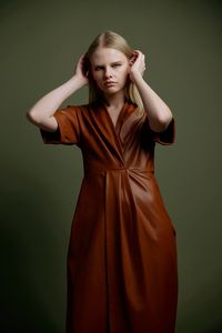 Portrait of young woman standing against yellow background