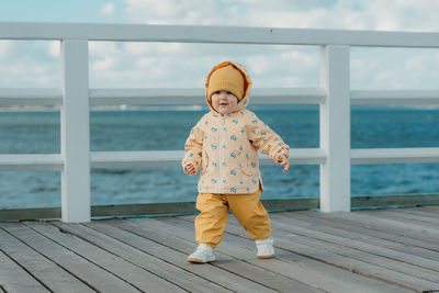 Portrait of boy standing on pier at beach