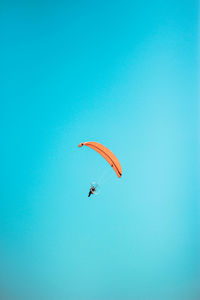 Low angle view of person paragliding against clear blue sky