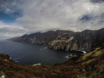 Scenic view of sea and mountains against sky