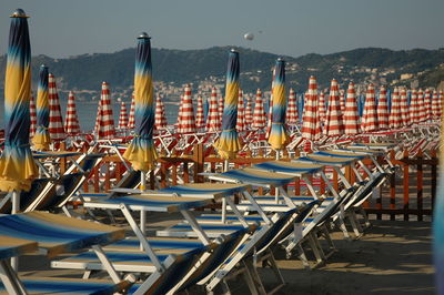 Chairs and tables at restaurant by sea against sky