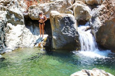 Full length of man standing on rock against waterfall