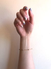 Cropped image of woman with painted fingernails against wall