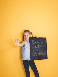 Portrait of smiling girl standing against yellow wall