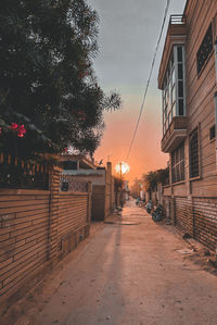 Street amidst buildings against sky during sunset